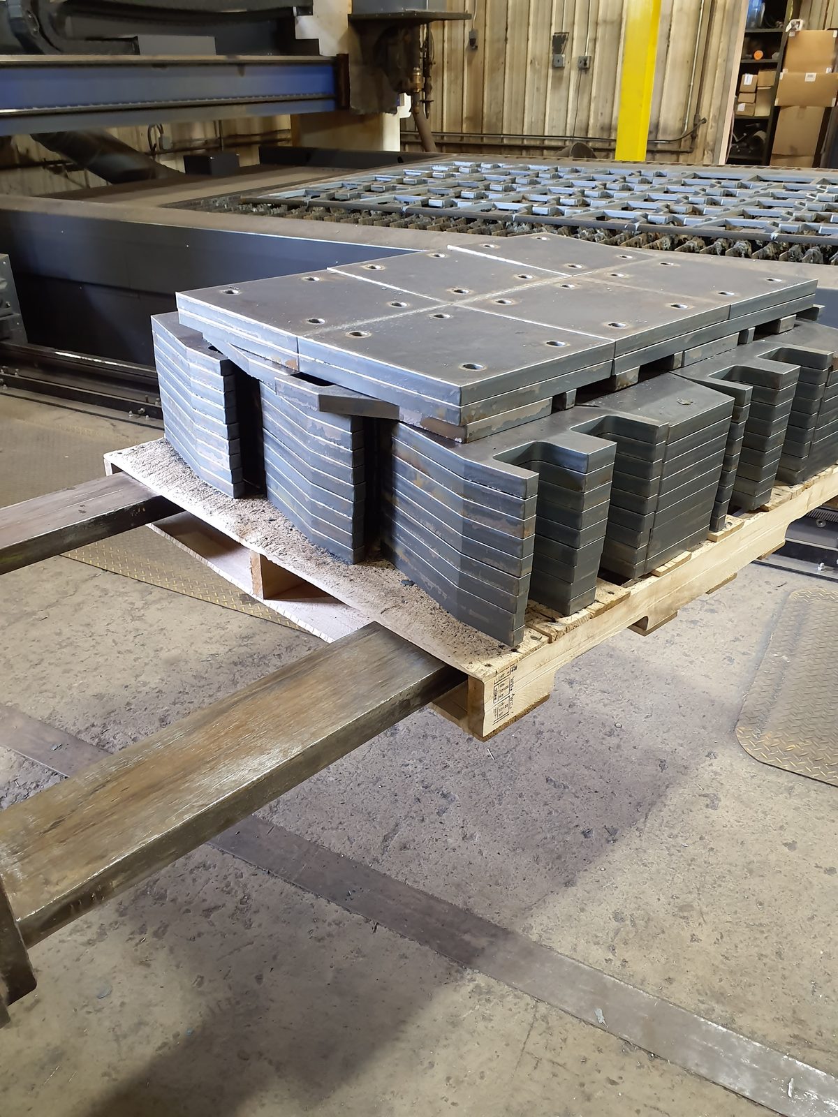 Machined steel plates staged at CNC fiber laser
